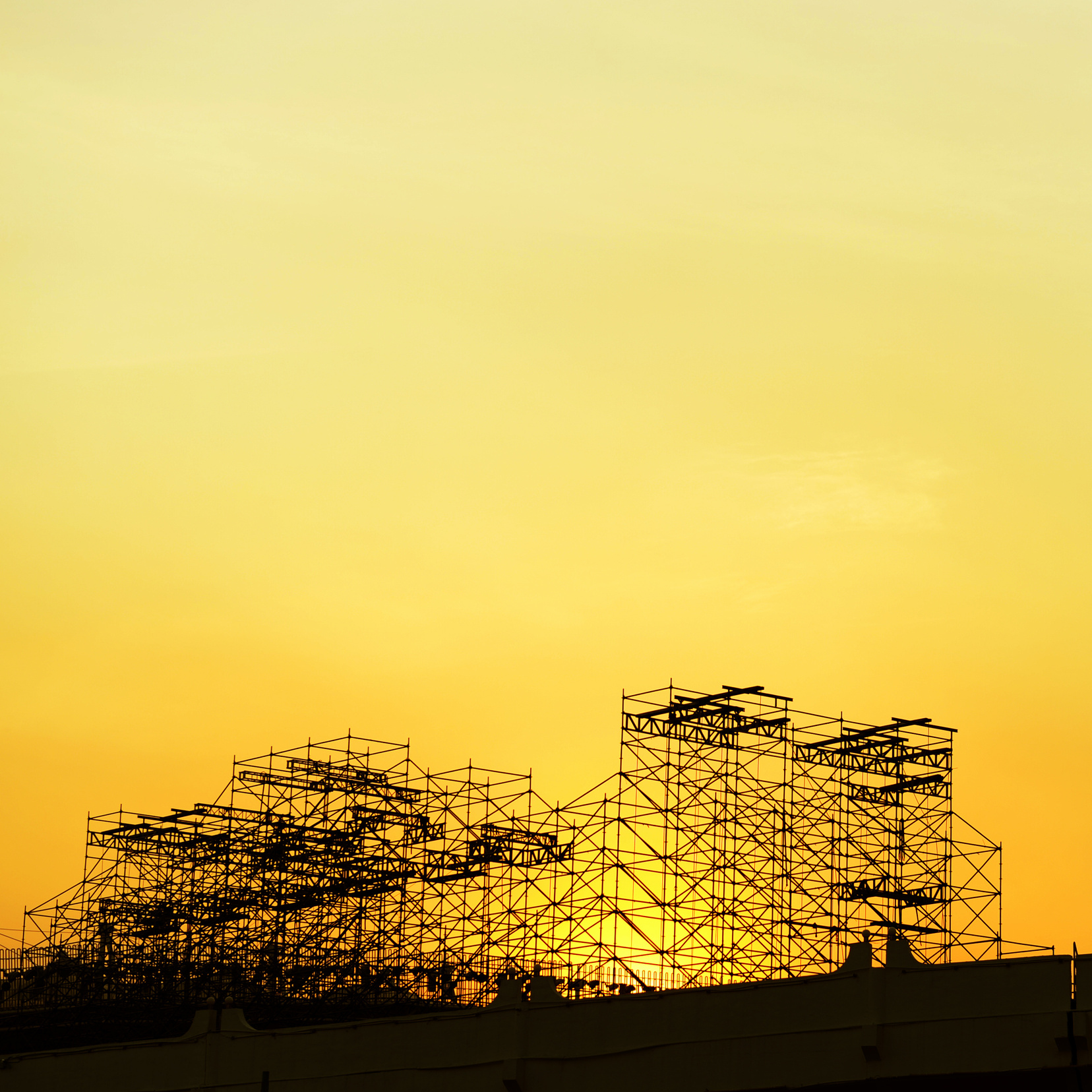 Scaffolding structures silhouetted against a sunset sky