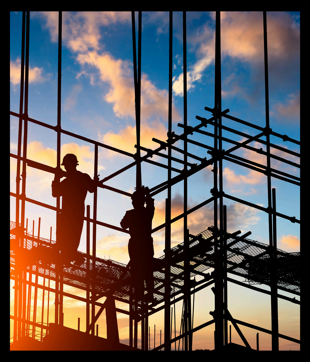 Construction workers on scaffolding at sunset